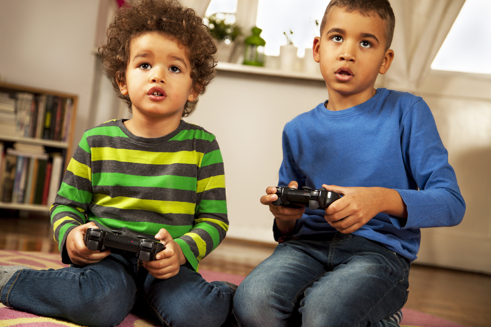A two boy sitting on the floor and playing video games